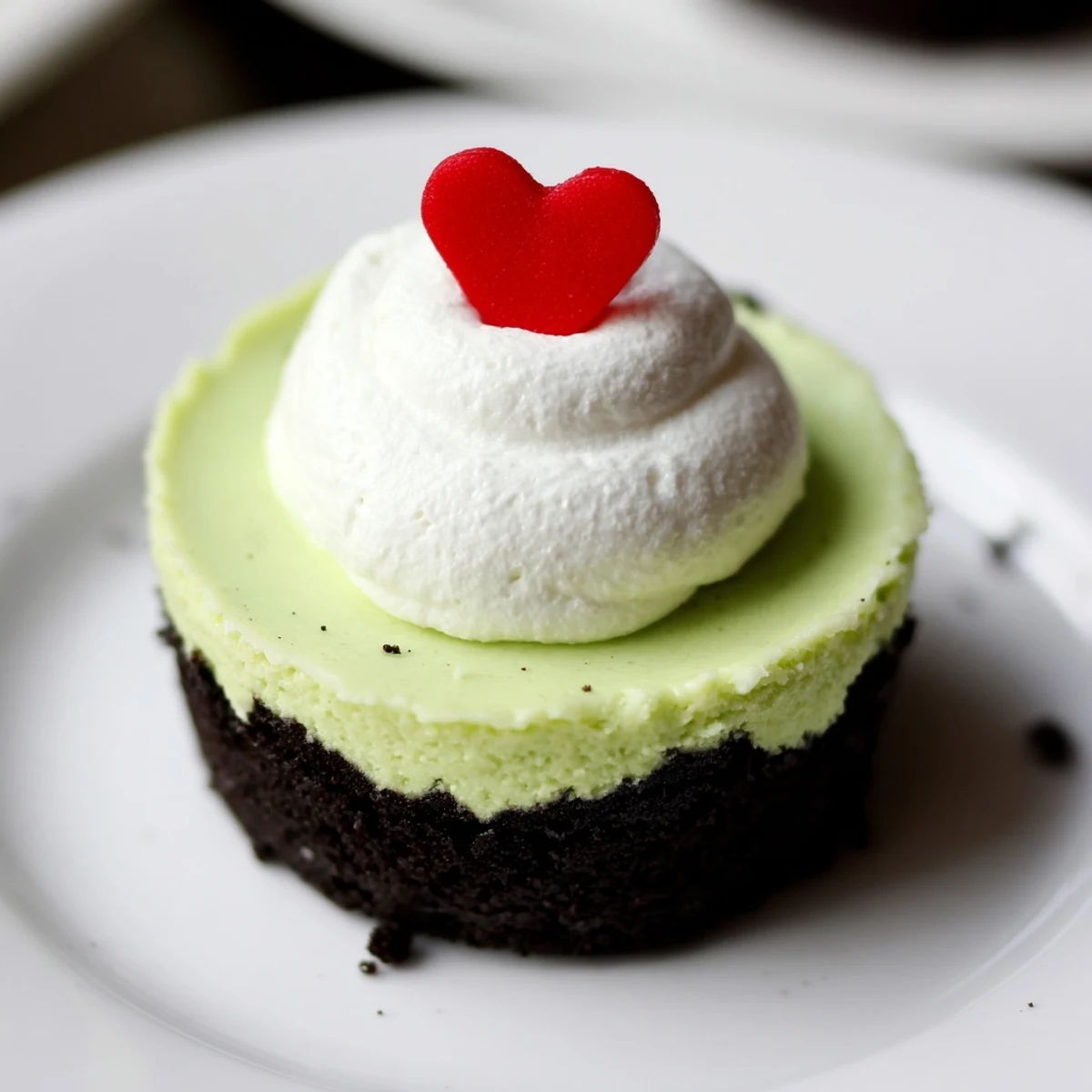 Festive Grinch Mini Cheesecakes, bright neon green, are topped with fluffy whipped cream and sprinkles.