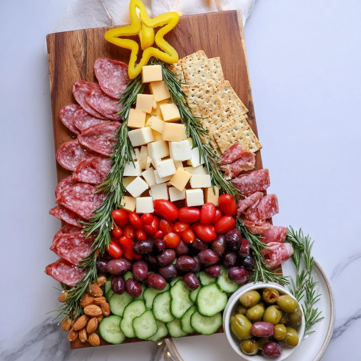 Christmas Tree Snack Board laden with colorful cheeses, meats, crackers, and olives, holiday ready.