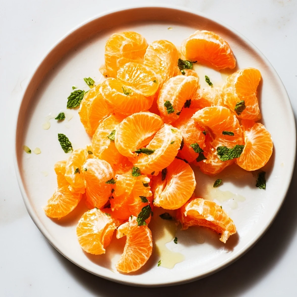 A bright bowl of clementine and mint winter fruit salad, ready to serve as a zesty dessert.