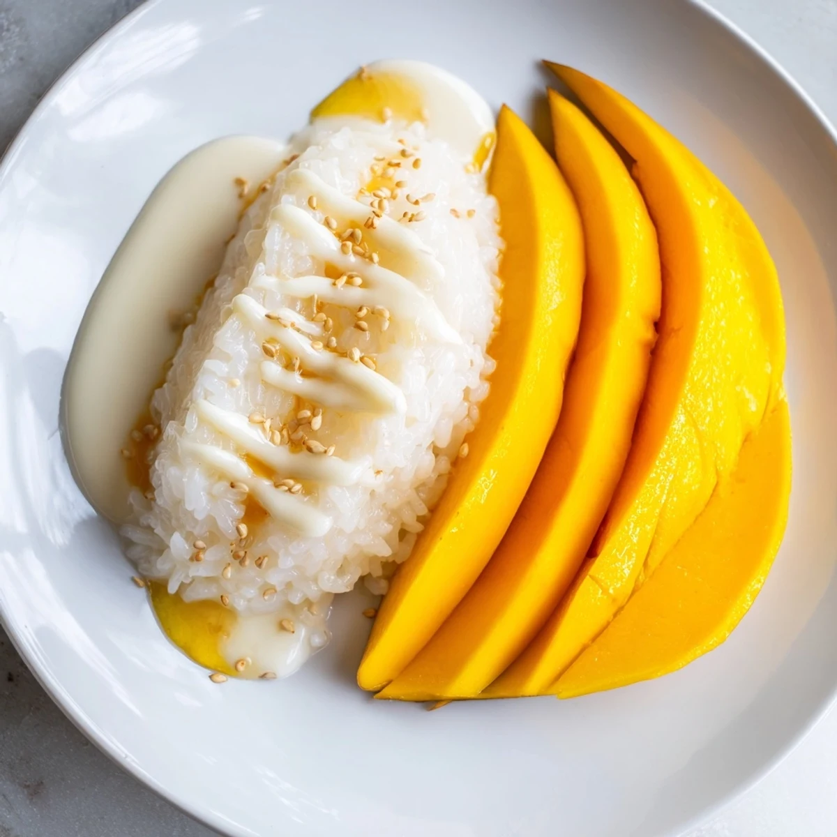 Sweet and savory, a plate of Thai Mango Sticky Rice with colorful mango and a drizzle of sauce.