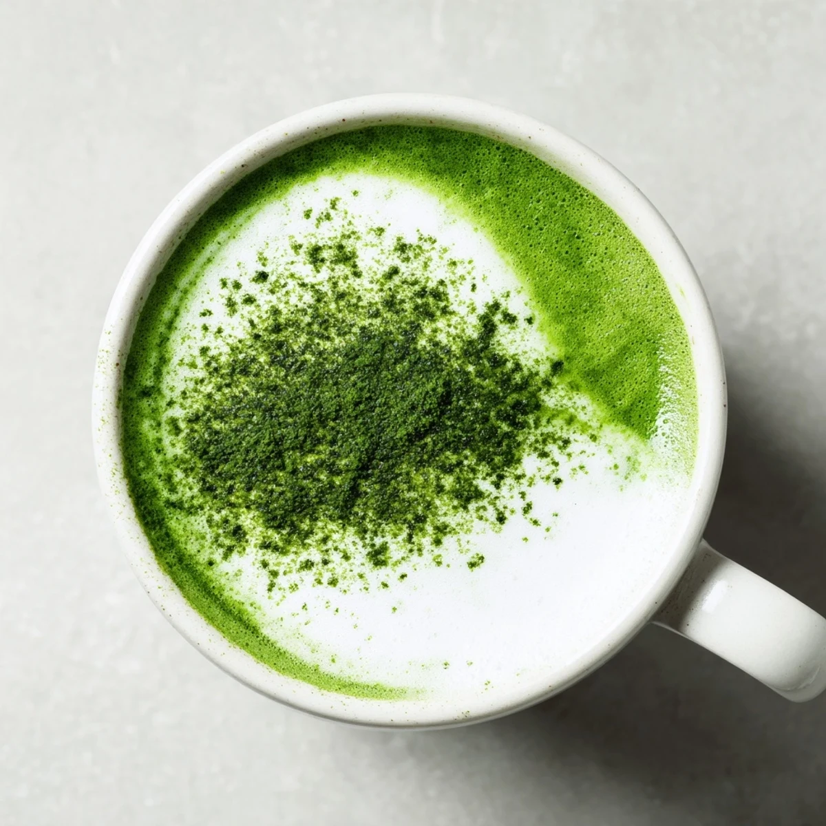 A frothy matcha green tea latte in a rustic ceramic mug, paired with a small bowl of honey and a fresh mint leaf garnish for an energizing treat.