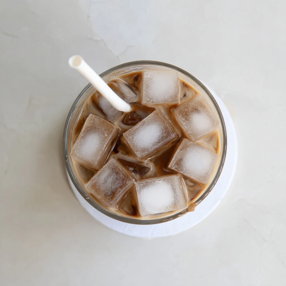 A spoonful of dark coffee jelly cubes sits atop a rich, milky beverage, garnished with cocoa powder for an indulgent Japanese fusion treat.