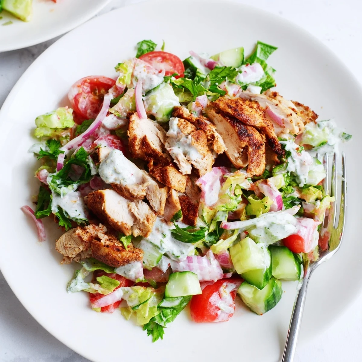 Golden, spice-rubbed shawarma chicken rests atop a vibrant Middle Eastern salad, garnished with fresh parsley and red onion slices.