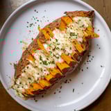 Golden, bubbly Sweet Potato & Cheese Whole Roast with herbs, ready for a comforting vegetarian dinner.