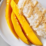 A close-up of glistening Thai Mango Sticky Rice, fragrant with coconut milk and topped with sesame seeds.