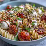 Vibrant summer pasta salad featuring al dente pasta, ripe cherry tomatoes, fresh mozzarella, and aromatic basil leaves.