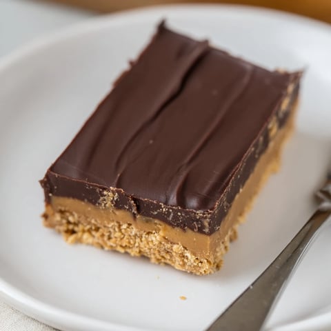 Rich no-bake peanut butter chocolate bars drizzled with velvety chocolate, perfect for dessert.  