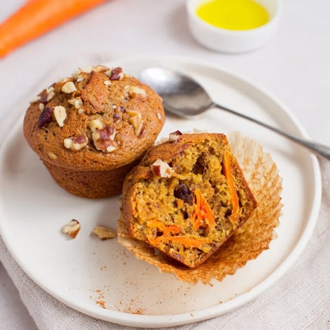 Moist spiced carrot cake muffins topped with walnuts and orange zest, perfect for brunch.  