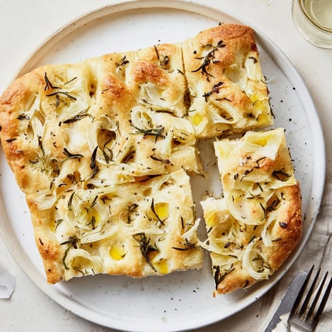 Fluffy cheesy herb focaccia drizzled with olive oil, garnished with fresh herbs.  