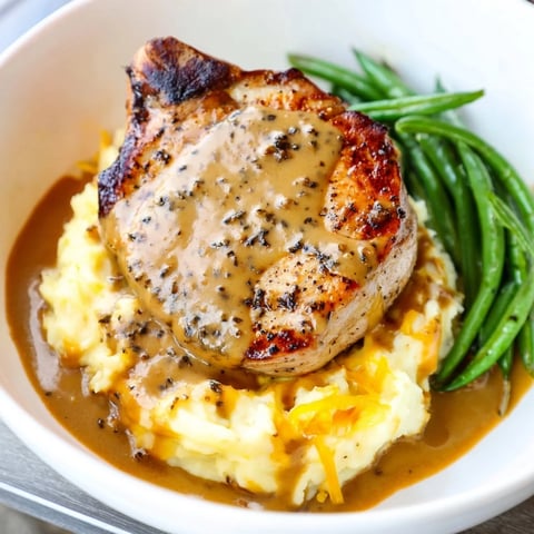 Sizzling pork chops sit atop creamy, cheesy cheddar mashed potatoes in this flavorful recipe.