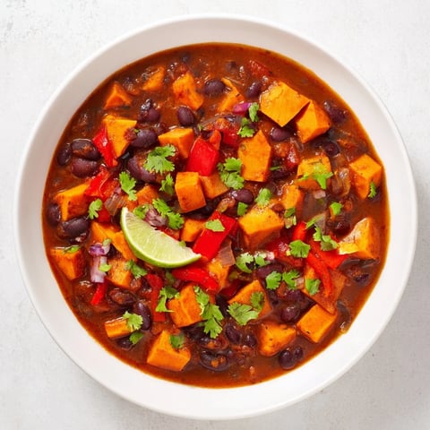 Steaming bowl of Sweet Potato & Black Bean Chili, garnished with cilantro and ready to serve.
