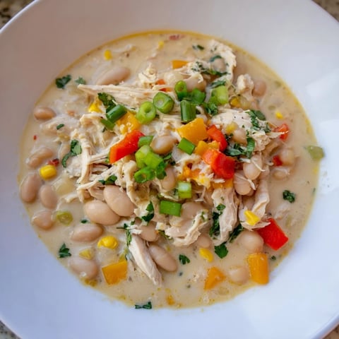 A warm bowl of creamy white chicken chili, ready to be served with garnishes.