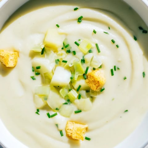 Steaming bowl of Potato Leek Soup, garnished with chives, a hearty and comforting vegetarian meal.
