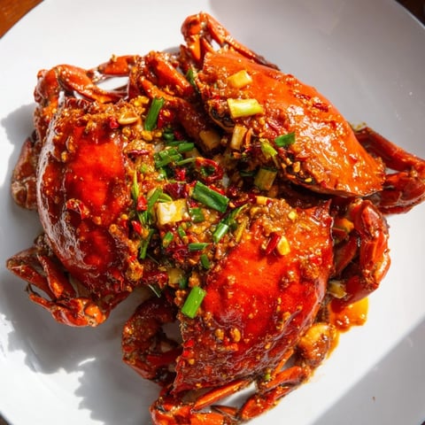 Steaming Singaporean Chili Crab, aromatic and spicy, with vibrant red crab pieces in sauce.