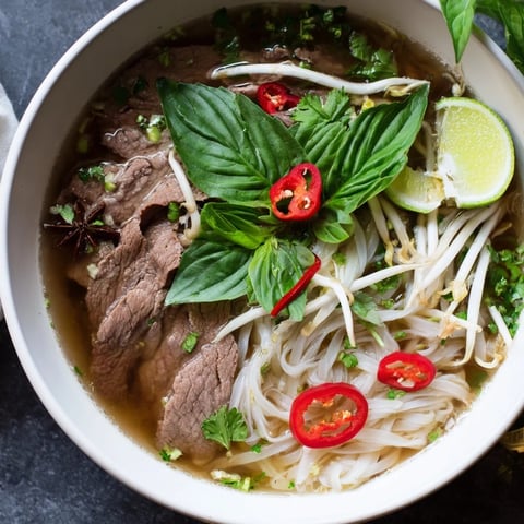 Steaming bowl of Vietnamese Pho Express, featuring tender beef and fragrant broth with fresh herbs.