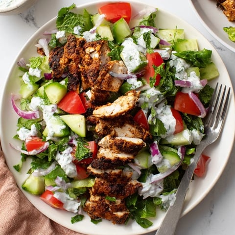 Freshly grilled chicken shawarma slices over a bed of crisp cucumber, tomato, and mixed greens, all drizzled with creamy Greek yogurt dressing.