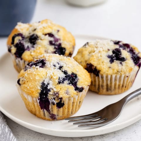 Fluffy blueberry muffins just out of the oven, invitingly warm with a sugary crust.  
