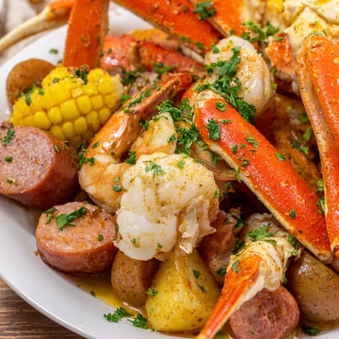 A close-up shot of the seafood boil showcases juicy crab legs, shrimp, and sausage.