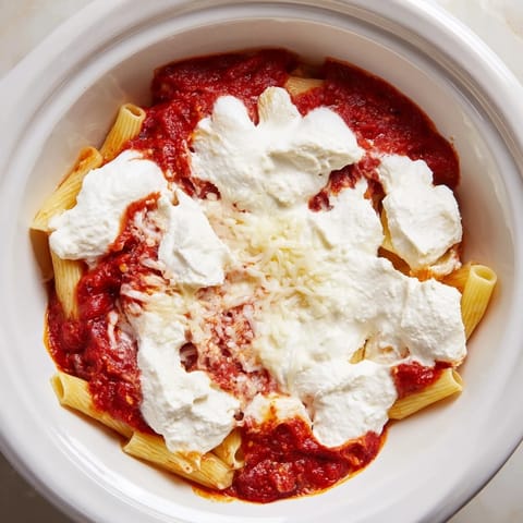 A close-up of cheesy, bubbling slow cooker baked ziti, a comforting Italian-American family dinner.