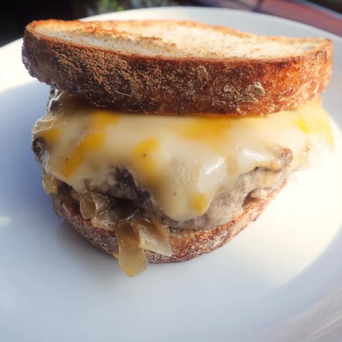 A close-up shot of a savory Patty Melt Skillet with onions and melted cheese on rye.