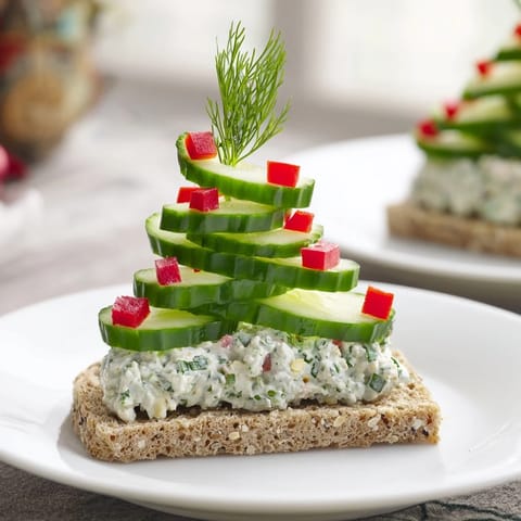 Vibrant Cucumber and Cream Cheese Tree Stacks appetizer, garnished with red pepper and dill sprigs.