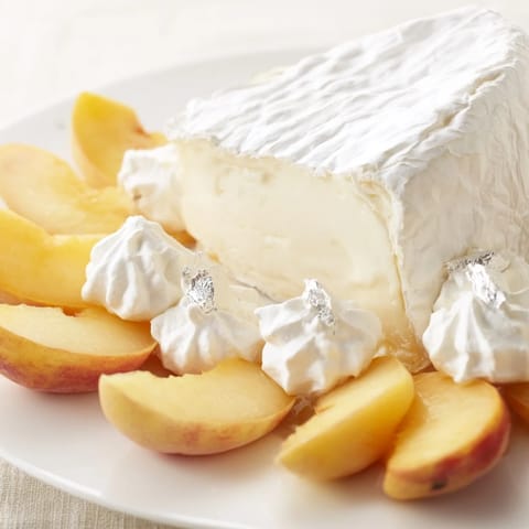 Freshly arranged The Pearly Gates cheese board showcases creamy brie surrounded by sweet peaches and edible silver.