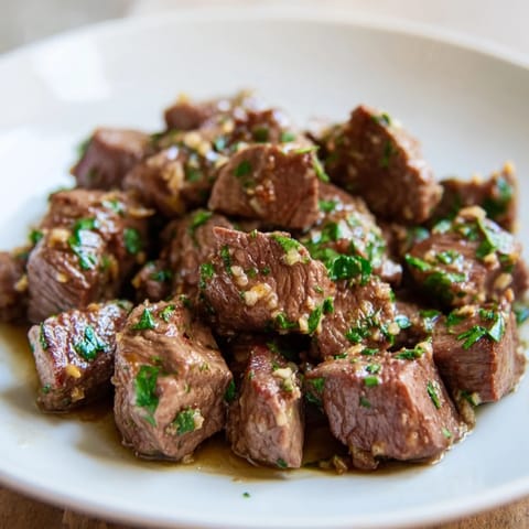 Tender, juicy air-fryer garlic-butter steak bites, sizzling from the air fryer, and coated in garlic butter.