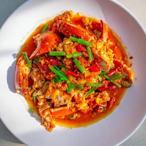 Close-up of bubbling Singaporean Chili Crab, showcasing tender crab meat and rich, flavorful sauce.