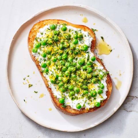 Vibrant green pea and mint ricotta spread on crunchy toast, served with fresh lemon wedges.