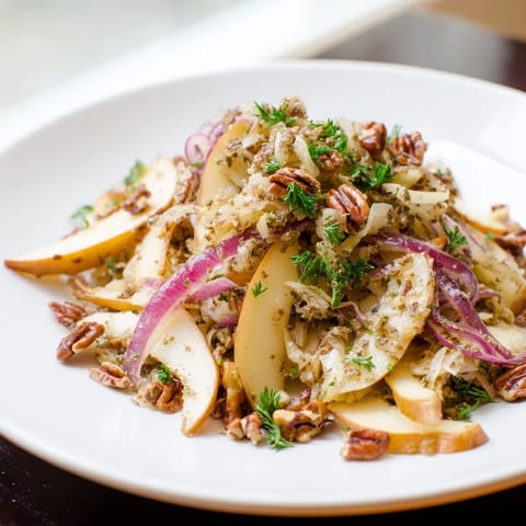 Golden Honeycrisp apples and red onions caramelizing in a skillet, topped with fresh sauerkraut and parsley for a warm, tangy salad.  