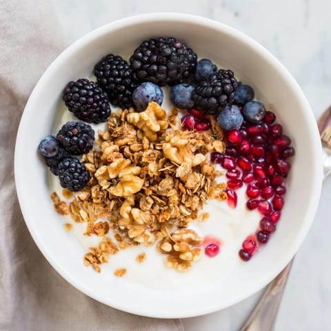 Creamy probiotic yogurt topped with spiced crunch and jewel-toned winter berries in a cozy breakfast bowl.