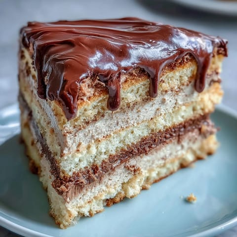 A close-up view of the hojicha butter cream cake reveals its tender sponge layers, creamy matcha-colored filling, and a smooth chocolate topping, ready for a tea party.