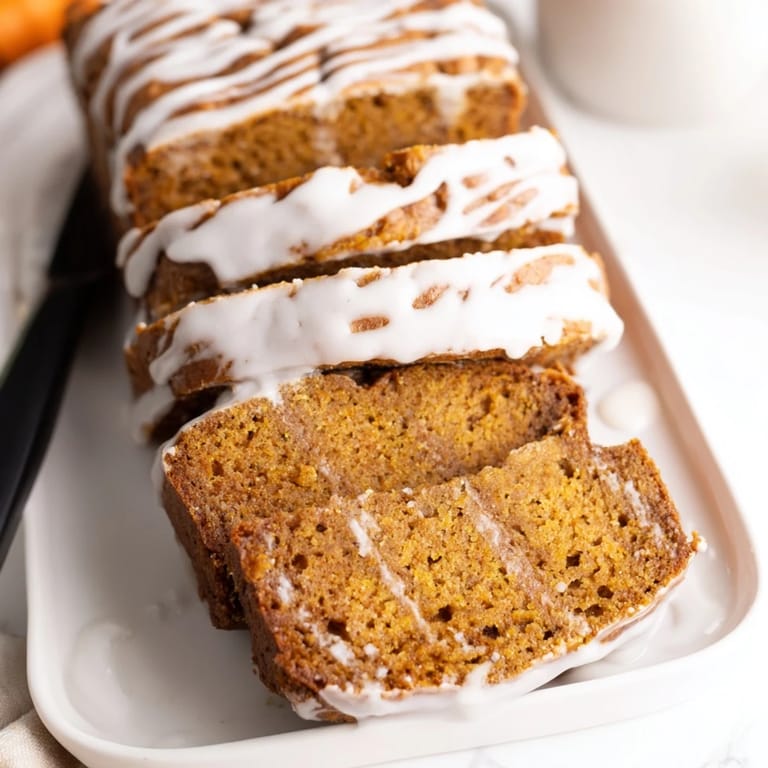 Warm, spiced pumpkin loaf topped with creamy glaze, a treat for autumn gatherings.