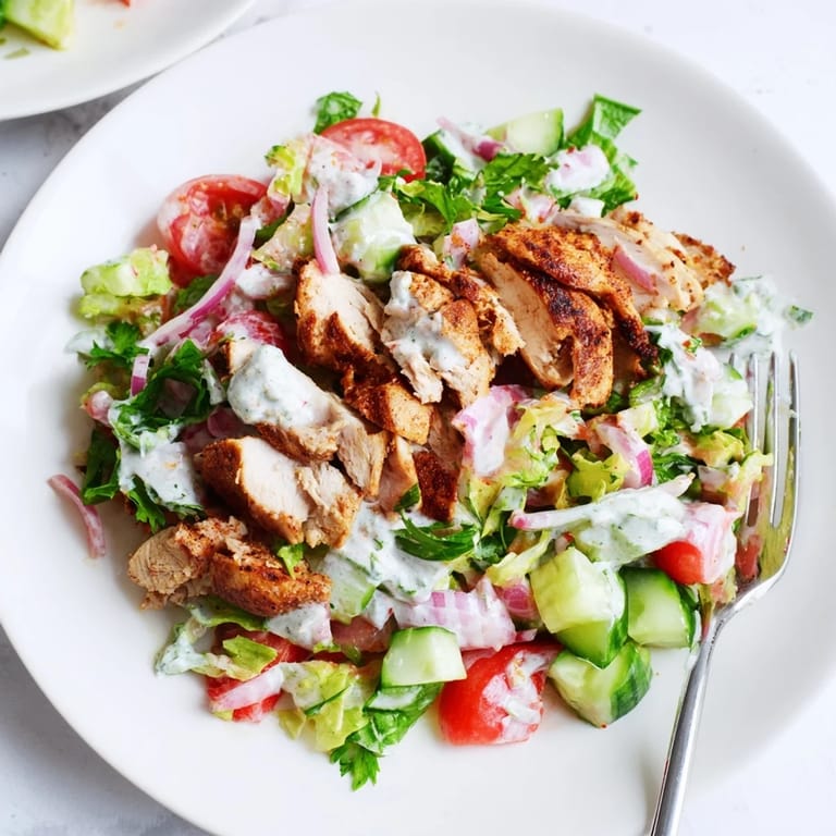 Golden, spice-rubbed shawarma chicken rests atop a vibrant Middle Eastern salad, garnished with fresh parsley and red onion slices.
