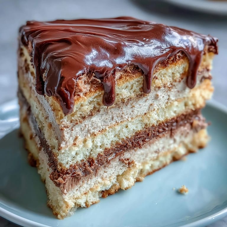 A close-up view of the hojicha butter cream cake reveals its tender sponge layers, creamy matcha-colored filling, and a smooth chocolate topping, ready for a tea party.