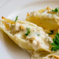 Golden-baked Chicken Alfredo Stuffed Shells emerge from the oven with bubbling, melted cheese.  