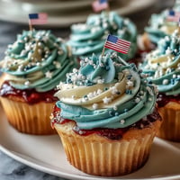 Festive Star-Spangled Banner Cupcakes with swirled patriotic frosting and an edible flag topper.